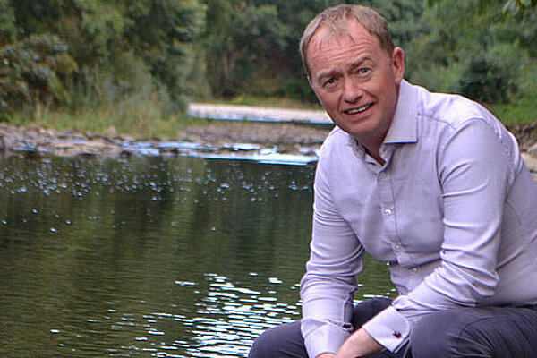 MP Tim Farron squatting by the River Lune