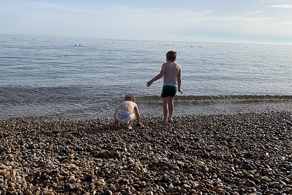 sea shore image with two small children facing out to sea